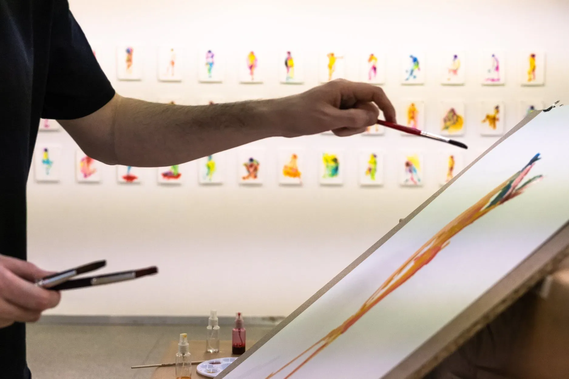 Marçal drawing a large-format figure on the gallery wall